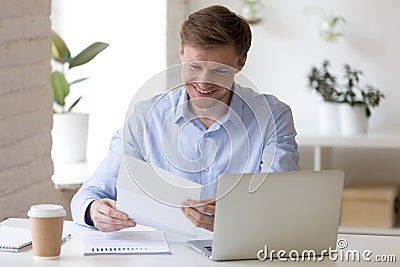 Satisfied businessman sitting at the desk reading letter Stock Photo