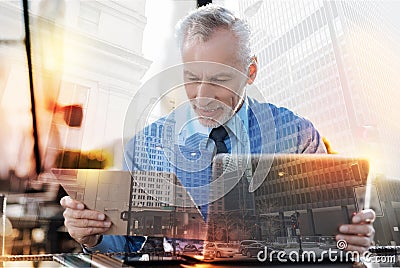 Experienced employer looking at the documents while sitting with his laptop Stock Photo