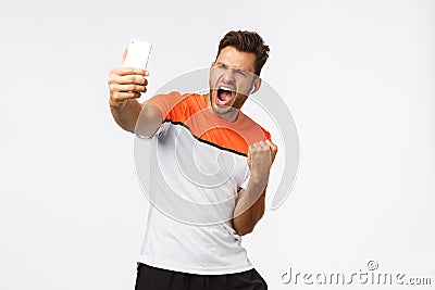 Satisfied handsome male athlete in sports t-shirt winning award, sharing great news, achievement social media followers Stock Photo