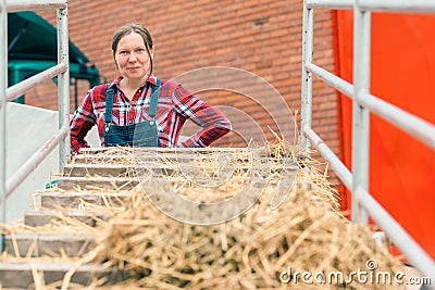 Satisfied happy female farmer with hay wagon Stock Photo