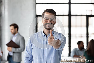 Satisfied loyal male client posing in office raising thumb up Stock Photo