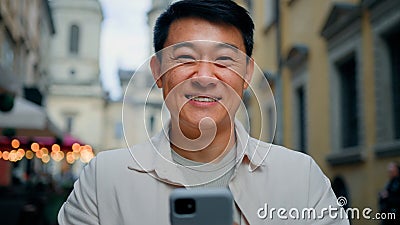 Satisfied man customer client standing outdoors holding mobile phone looking at camera enjoys internet shopping on Stock Photo