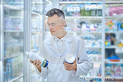 Satisfied man in white coat holding medical products Stock Photo
