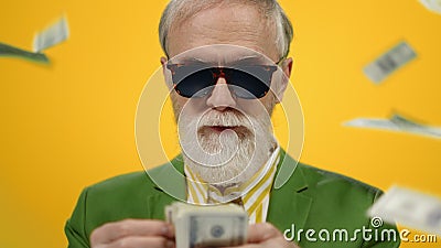 Satisfied old man staying under money rain. Mature guy counting dollars indoors. Stock Photo