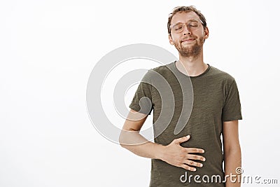 Satisfied and pleased male visiting favorite restaurant licking lips and closing eyes rubbing belly from delight and Stock Photo