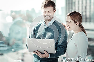 Satisfied responsible man standing and holding the laptop. Stock Photo