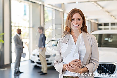 Satisfied saleswoman in car dealership Stock Photo