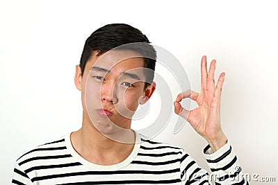 Satisfied young Asian man giving the okay sign and looking at ca Stock Photo