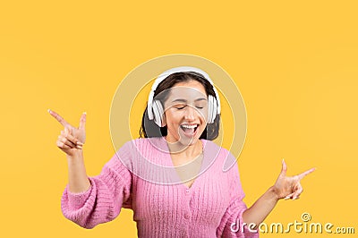 Satisfied young islamic female in wireless earphone has fun, dancing, enjoys free time, listen music, sing Stock Photo