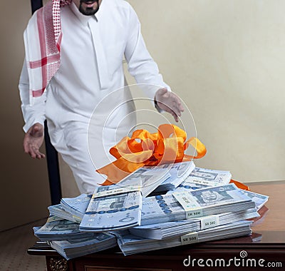 Saudi Arab man surprized with stacks of money on the table Stock Photo