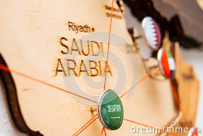 Saudi Arabia flag on the pushpin and red threads on the wooden map Stock Photo
