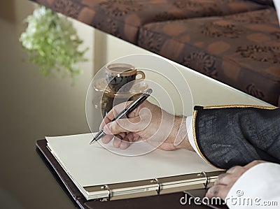 Saudi Arabian Man Hand Writing on A Notebook Stock Photo
