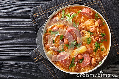 Sauerkraut stew with borlotti beans, potatoes and sausages close-up in a bowl. horizontal top view Stock Photo