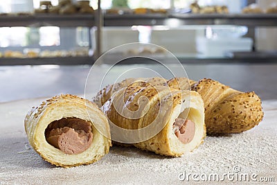 Sausage Rolls With Sesame Cut in Half on Floury Wooden Table Stock Photo