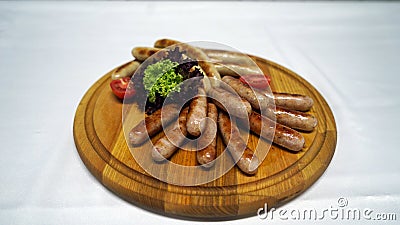 Juicy sausages cooked on a grill, baked crust and served with fresh vegetables on the wood Stock Photo