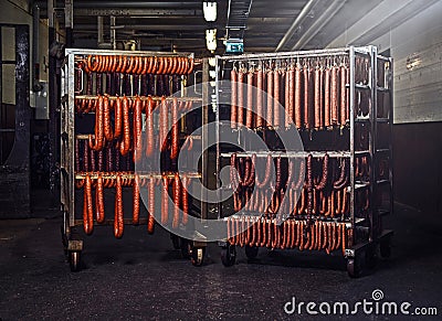 Sausages on racks in a storage room in meat processing factory. Stock Photo