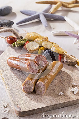 Saussages with scallop skewers on cutting board on the beach Stock Photo