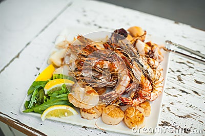 Saute shrimps, scallop, squid and lemon on white plate in the restaurant. Stock Photo