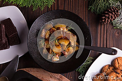 Sauteed sweet potato salad on black bowl on brown wooden background. Side dish for christmas, thanksgiving, and new year's eve din Stock Photo