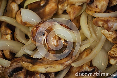 Sauteing mushrooms and onions in a frying pan with oil, seasoning, and steam Stock Photo