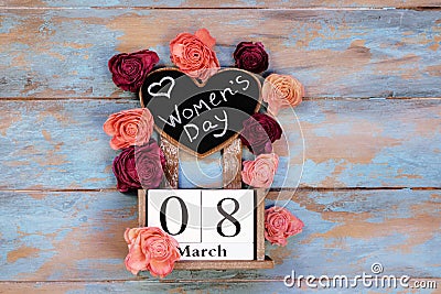 Save the date block calendar for International Womens day, March 8, with chalkboard, next to roses flowers, on blue Stock Photo