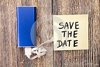 Save the Date sticky note paper charging with energy bank. Depth of field on Power bank Stock Photo