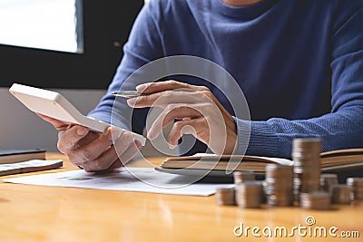 Saving concept The male money saver attempting to count his income this month and other past old months by using a calculator Stock Photo
