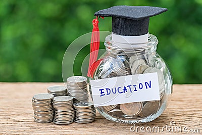 Saving for education with coins in jar and graduates hat label a Stock Photo