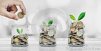 Saving money, Banking and Investment concepts, Hand putting coin in glass bottles with plants glowing Stock Photo