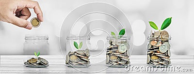 Saving money and investment concepts, Hand putting coin in glass bottles with plants glowing Stock Photo