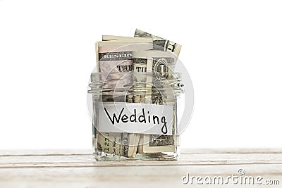 Saving money for wedding. Glass jar with us dollars on wooden table isolated Stock Photo