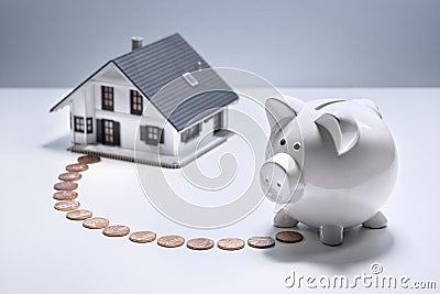 Saving to buy a house, piggy bank with coin path to model home Stock Photo