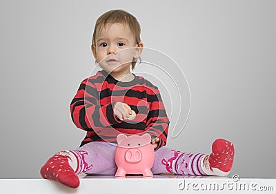 Savings and banking concept. Child girl is putting coins in piggy money bank Stock Photo