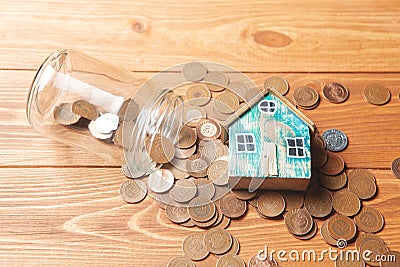 Savings concept for home. Coins are pouring from the piggy bank and the house is on them Stock Photo