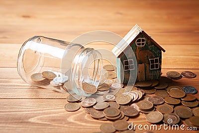 Savings concept for home. Coins are pouring from the piggy bank and the house is on them Stock Photo