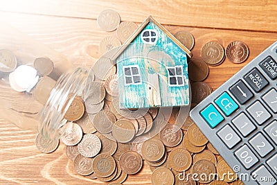 Savings concept for home. Coins are pouring from the piggy bank and the house is on them Stock Photo