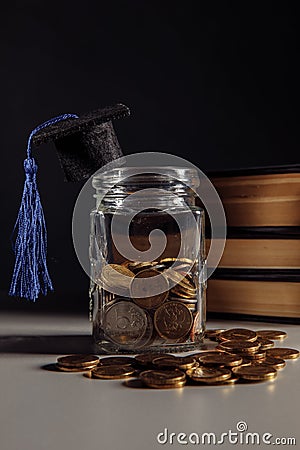Savings for education concept. Coins in jar with coins and books. Vertical image Stock Photo
