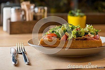 Savory Belgian waffles with balyk, salad and tomato. Perfect breakfast for long day. Restaurant menu or recipe concept Stock Photo