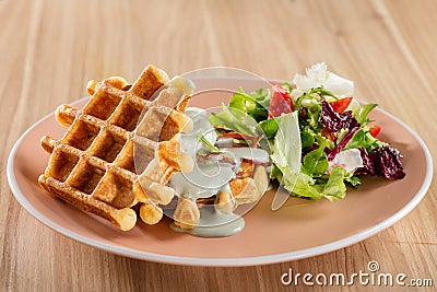 Savory Belgian waffles with cheese sauce and salad Stock Photo