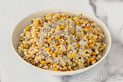 A savory blend of pearled couscous, orzo, baby garbanzo beans, and red quinoa, cooked, and served in a bowl Stock Photo