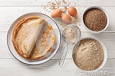 Savory crepes Buckwheat Galettes closeup on a plate with ingredients flour, cereal and eggs closeup on the wooden table. Stock Photo