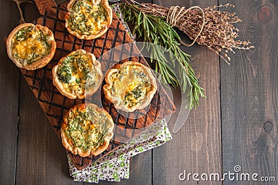 Savory mini quiches tarts on a wooden board. Flaky dough pies. Stock Photo