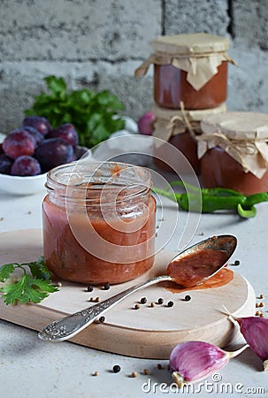 Savory sauce from red plums, garlic, cilantro, dill and hot pepper. Georgian tkemali on white background. Autumn canning and prese Stock Photo