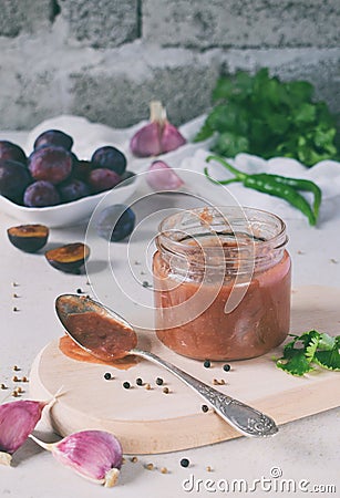 Savory sauce from red plums, garlic, cilantro, dill and hot pepper. Georgian tkemali on white background. Autumn canning and prese Stock Photo