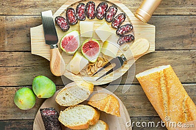 Savory and sweet snack and appetizers board with variety of meat charcuterie cheese nuts figs french baguette on wood platter Stock Photo