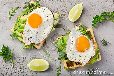 Savory waffles with avocado, arugula and fried egg for breakfast Stock Photo