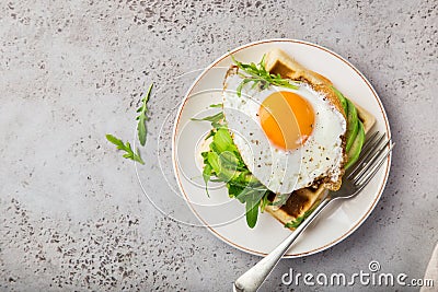 Savory waffles with avocado, arugula and fried egg for breakfast Stock Photo