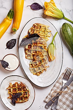Savory zucchini waffles with herbs served with sour cream sauce. Top view. Stock Photo