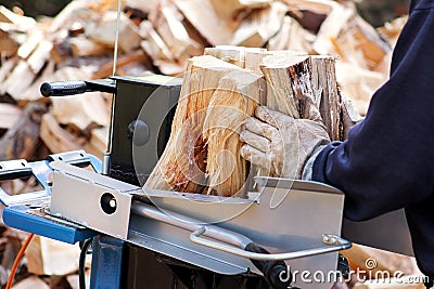 Saw cutting wood for winter. A man cutting firewood for the winter using a modern machine lumber saw. Stock Photo