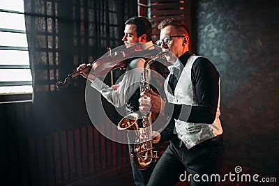 Sax man and fiddler duet playing classical melody Stock Photo